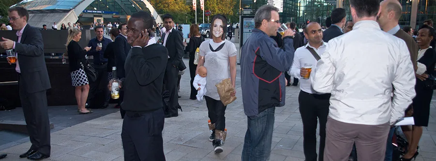 Chi in costume, with mask, bump and baby doll, walking unnoticed through a crowd at Canary Wharf